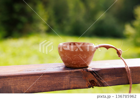 Handcrafted wooden cup resting on rustic wooden railing surrounded by lush green landscape Handcrafted wooden cup resting on rustic wooden railing surrounded by lush green landscape 136785962