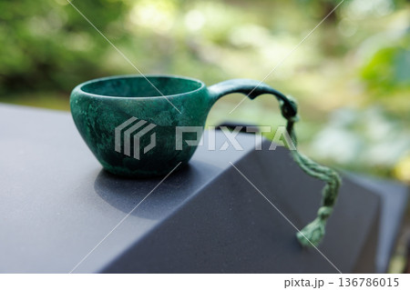 Elegant green cup resting on a smooth surface in a serene garden setting 136786015
