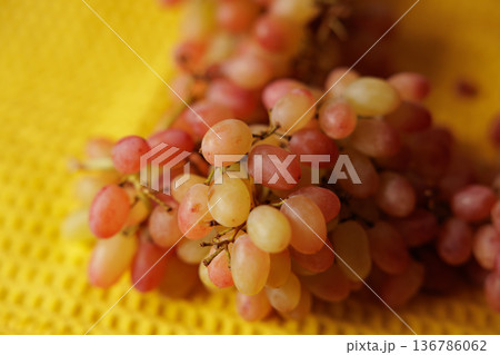 Fresh and vibrant grapes ready to delight on a sunny yellow surface 136786062