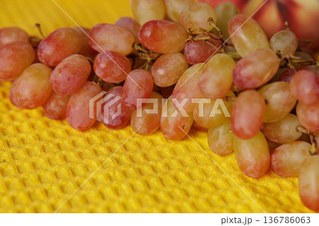 Juicy grapes laid upon a vibrant yellow cloth, bringing life to a sunny kitchen moment 136786063