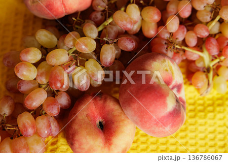 Bright and colorful grapes and peaches resting on a sunny yellow surface, showcasing nature's bounty and beauty 136786067
