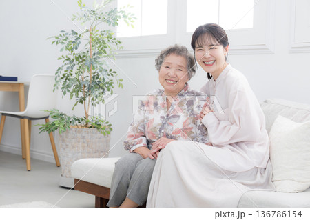 孫と高齢の祖母の笑顔の寄り添うクローズアップ　介護や親子のイメージの全身	 136786154