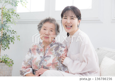 孫と高齢の祖母の笑顔の寄り添うクローズアップ　介護や親子のイメージのカメラ目線	 136786156