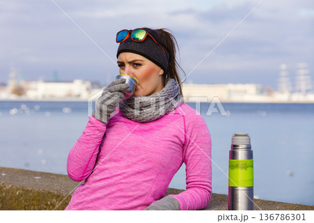 Fit woman in cold day warming up drink tea Fit woman in cold day warming up drink tea 136786301