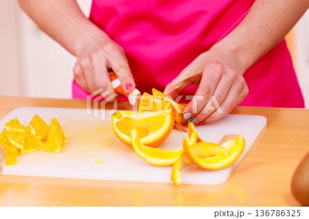 Woman housewife in kitchen cutting orange fruits Woman housewife in kitchen cutting orange fruits 136786325