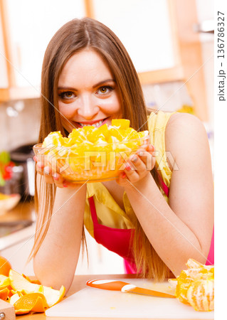 Woman holds bowl full of sliced orange fruits 136786327