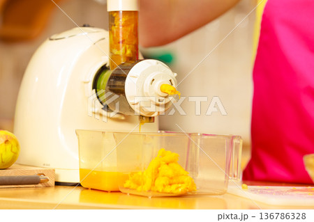 Making orange juice in juicer machine in kitchen 136786328