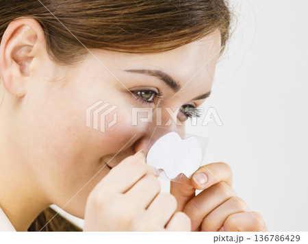 Woman applying pore strips on nose 136786429