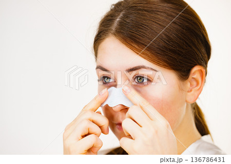 Woman applying pore strips on nose Woman applying pore strips on nose 136786431