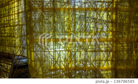 Yellow mesh construction scaffolding illuminated during evening Feb 5 2026 136786585
