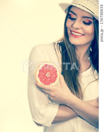 Woman holding half of grapefruit citrus fruit in hand Woman holding half of grapefruit citrus fruit in hand 136786638