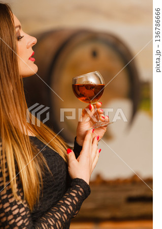 Woman tasting wine in rural cottage interior Woman tasting wine in rural cottage interior 136786666