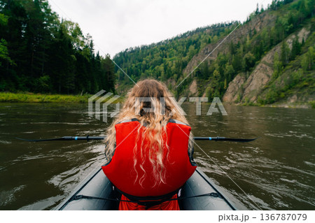Girl in a life jacket rafting on a packraft on the river 136787079