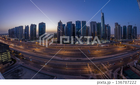 Aerial view of Jumeirah lakes towers skyscrapers night to day timelapse with traffic on sheikh zayed road. Aerial view of Jumeirah lakes towers skyscrapers night to day timelapse with traffic on sheikh zayed road. 136787222