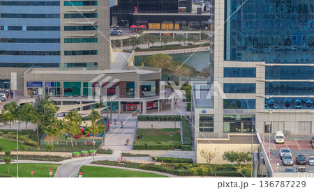 Aerial view of green area near Jumeirah lakes towers skyscrapers timelapse with car parking Aerial view of green area near Jumeirah lakes towers skyscrapers timelapse with car parking 136787229