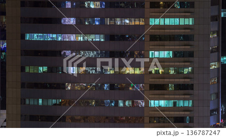 Windows of the multi-storey building of glass and steel lighting inside and moving people within timelapse Windows of the multi-storey building of glass and steel lighting inside and moving people within timelapse 136787247