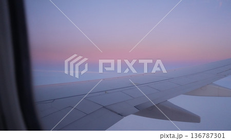 Airplane wing view during sunset with colorful sky and clouds Airplane wing view during sunset with colorful sky and clouds 136787301