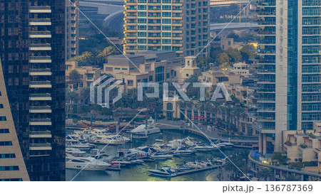 Promenade and canal in Dubai Marina with luxury skyscrapers and yachts around timelapse, United Arab Emirates 136787369