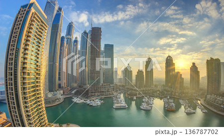 View of modern skyscrapers shining in sunrise lights timelapse in Dubai Marina in Dubai, UAE. View of modern skyscrapers shining in sunrise lights timelapse in Dubai Marina in Dubai, UAE. 136787702