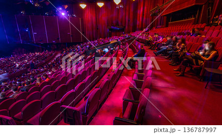 Spectators gather in the auditorium and watch the show in theatre timelapse. Large hall with red armchairs seats Spectators gather in the auditorium and watch the show in theatre timelapse. Large hall with red armchairs seats 136787997