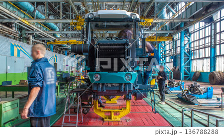 Conveyor assembly stage the body of tractor at big industrial factory timelapse Conveyor assembly stage the body of tractor at big industrial factory timelapse 136788288