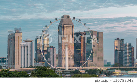 Skyline of Singapore with famous Singapore Ferries Wheel night to day timelapse 136788348