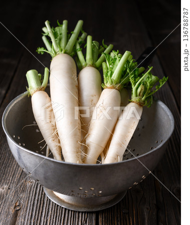 Daikon radish in metal colander on wooden table 136788787