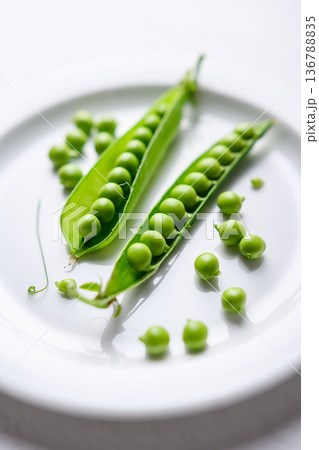Green peas and pods on a white plate as natural food ingredients 136788835