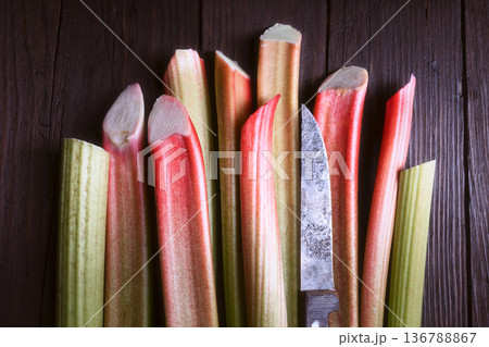 Rhubarb stems standing vertically on dark wood background 136788867