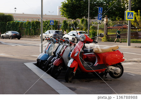Colorful scooters parked neatly along a city street in the afternoon light 136788988