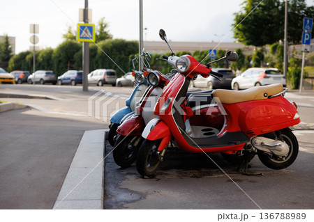 Colorful scooters parked together in a city street during a sunny afternoon Colorful scooters parked together in a city street during a sunny afternoon 136788989