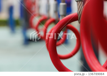 Colorful red gym rings hang in a playground setting providing a space for fitness and fun activities 136789064