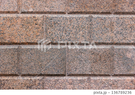 Red gray, speckled granite block wall with beveled joints 136789236