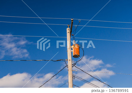 Electric transformer mounted on wooden utility pole in USA against blue sky Electric transformer mounted on wooden utility pole in USA against blue sky 136789591
