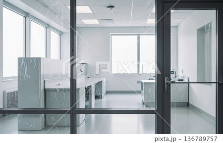 Laboratory cleanroom sterile view of empty pharmaceutical facility through glass window with workstations Laboratory cleanroom sterile view of empty pharmaceutical facility through glass window with workstations 136789757