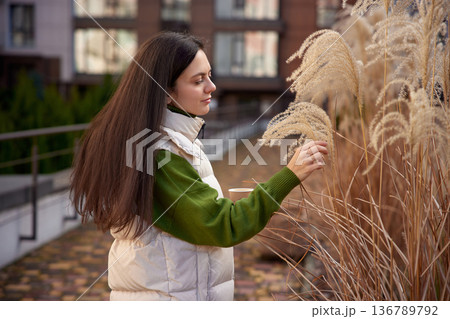 Woman touching pampas grass in an urban area during autumn 136789792