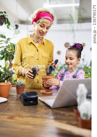 A woman and a young girl enjoy a gardening activity, learning and having fun together A woman and a young girl enjoy a gardening activity, learning and having fun together 136790175