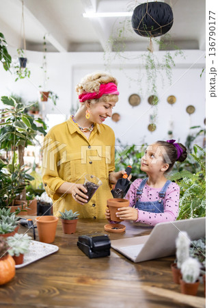 A woman and a young girl are potting plants, creating a heartwarming scene of family and gardening 136790177