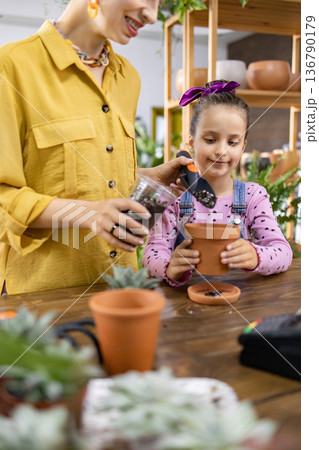 A young girl learns about gardening with her mother, enjoying a fun activity together A young girl learns about gardening with her mother, enjoying a fun activity together 136790179