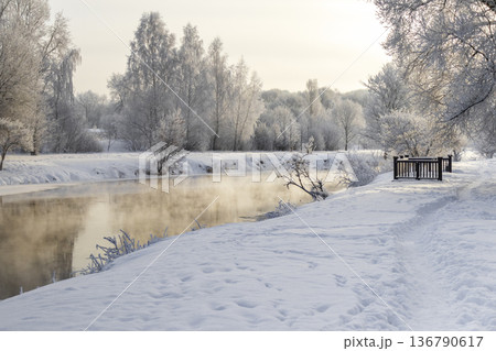 A winter scene with trees by the river covered in hoarfrost under a clear blue sky A winter scene with trees by the river covered in hoarfrost under a clear blue sky 136790617