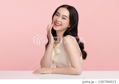 A beautiful young Asian woman with clean, fresh skin against a pink background. Skincare, facial treatment, cosmetology, beauty, and spa. An elegant portrait of an Asian woman. A beautiful young Asian woman with clean, fresh skin against a pink background. Skincare, facial treatment, cosmetology, beauty, and spa. An elegant portrait of an Asian woman. 136790813