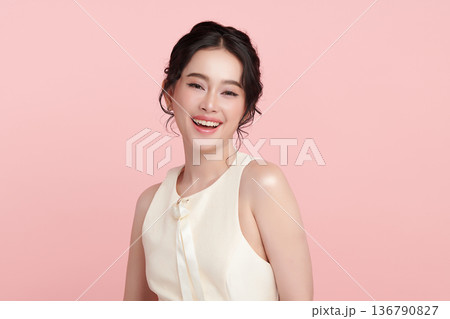 A beautiful young Asian woman with clean, fresh skin against a pink background. Skincare, facial treatment, cosmetology, beauty, and spa. An elegant portrait of an Asian woman. A beautiful young Asian woman with clean, fresh skin against a pink background. Skincare, facial treatment, cosmetology, beauty, and spa. An elegant portrait of an Asian woman. 136790827