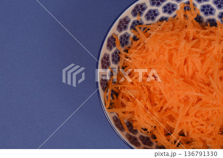 Grated Carrots in Ceramic Bowl on Blue Grated Carrots in Ceramic Bowl on Blue 136791330