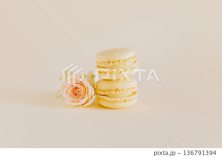 Tasty french macarons with tender rose flowers on a yellow pastel background. Tasty french macarons with tender rose flowers on a yellow pastel background. 136791394