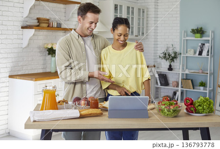 Couple cooking together at home kitchen, making salad with tablet recipe Couple cooking together at home kitchen, making salad with tablet recipe 136793778