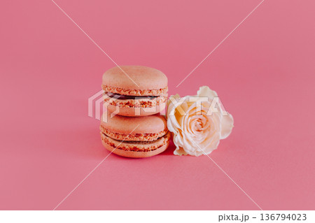 Tasty french macarons with tender rose flowers on a bright pink background. Tasty french macarons with tender rose flowers on a bright pink background. 136794023