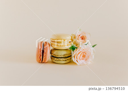 Tasty french macarons with tender rose flowers on a peach pastel background. 136794510