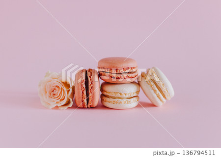 Tasty french macarons with tender rose flowers on a pink pastel background. 136794511