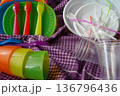 Reusable plastic picnic tableware versus disposable plastic tableware. Colorful and white plates, forks, and cups. Conscious consumption, product selection. A responsible approach to the environment. 136796436