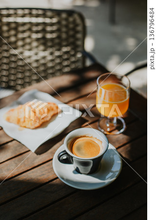 Cup of black coffee, a croissant and glass of fresh orange juice on a table in a street cafe. Cup of black coffee, a croissant and glass of fresh orange juice on a table in a street cafe. 136796484